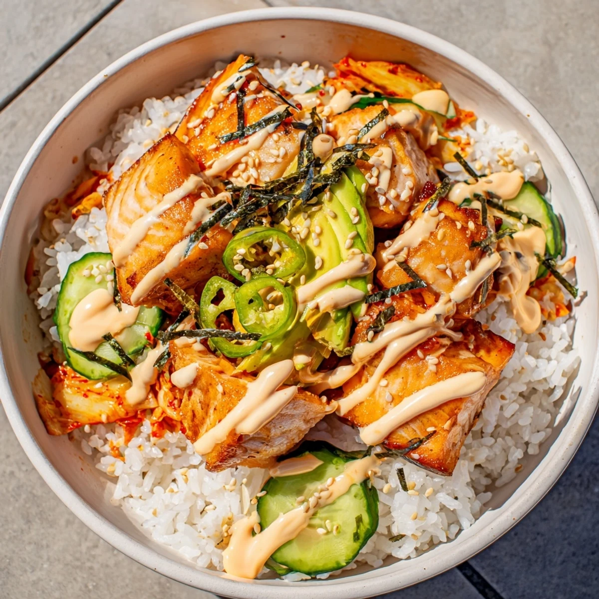 Crispy salmon rice bowl topped with spicy mayo, fresh avocado, and tangy kimchi.