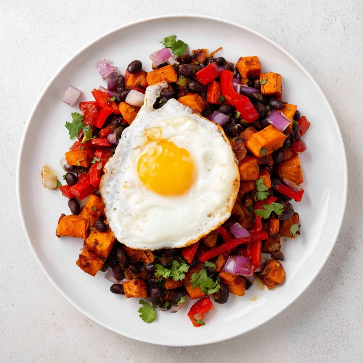 Savory Sweet Potato & Black Bean Breakfast Hash, topped with perfectly cooked sunny-side-up eggs.