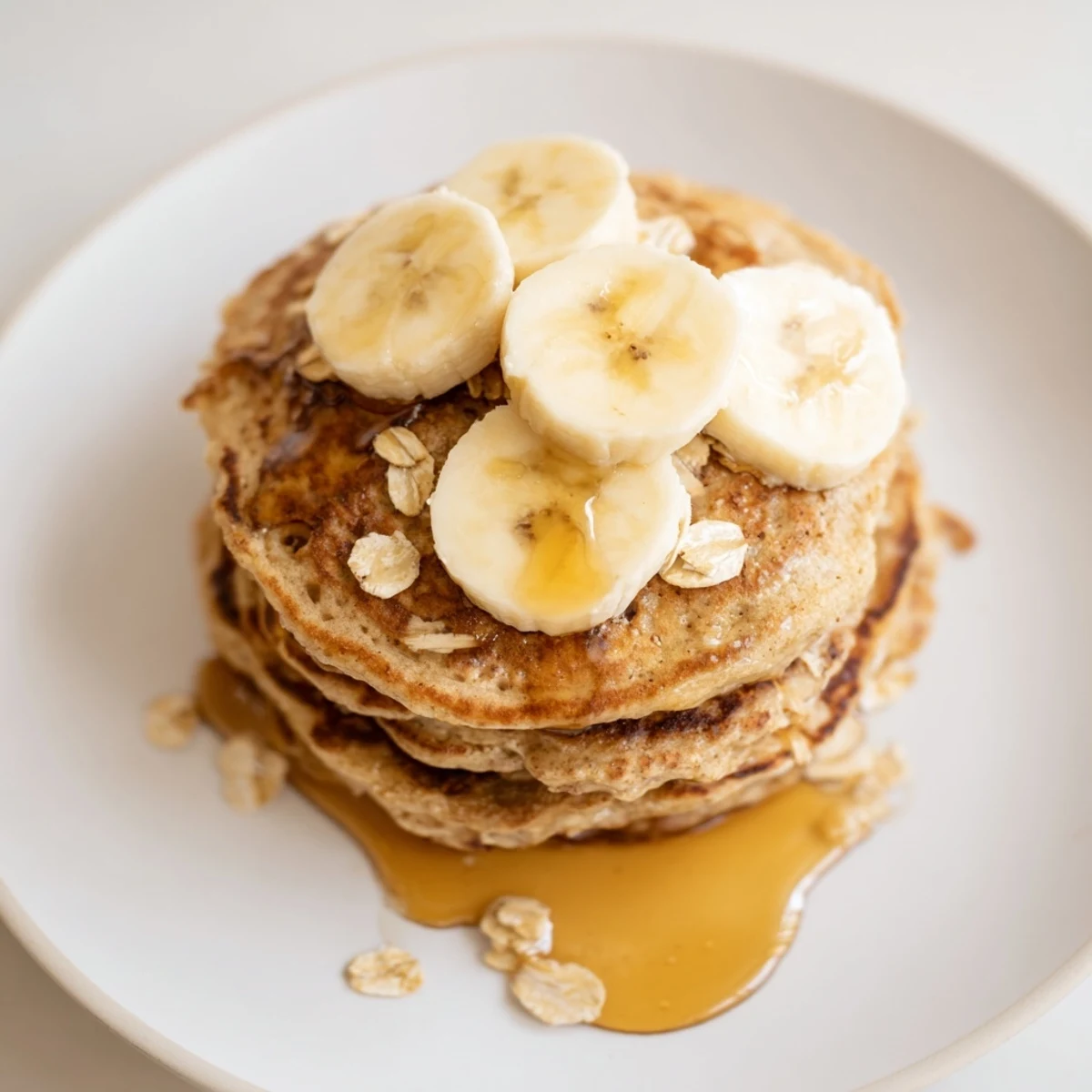 Homemade banana oat pancakes: pillowy and golden-brown, served with optional sliced bananas and yogurt.