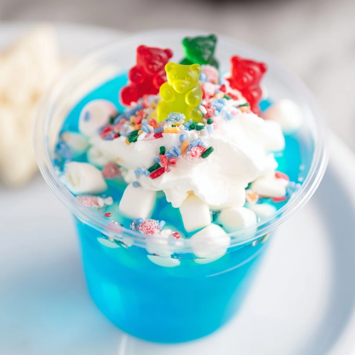 Festive snow globe Jello cups, homemade treats filled with candies and perfect for a holiday party.
