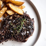 A close-up of a perfectly cooked Classic Peppercorn Ribeye alongside a generous portion of fries.