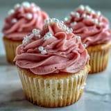Bridal shower vanilla cupcakes with pink frosting, topped with edible pearls for a festive dessert display.