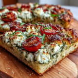 Golden baked cottage cheese flatbread, generously spread with vibrant pesto and juicy tomato halves.