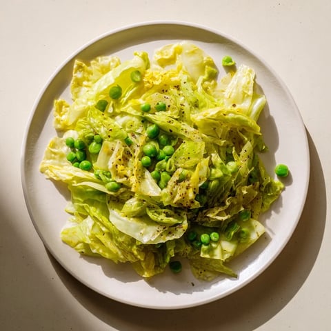 Steaming cabbage stir-fry with garlic, soy, and peas, ready to serve as a vegetarian side.