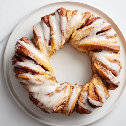 Fluffy, golden brown cinnamon roll pull-apart wreath, glazed and perfect for sharing at brunch.
