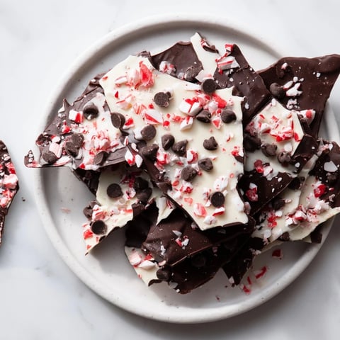 Peppermint bark shards scattered on a wooden board ready for sharing, a festive treat.