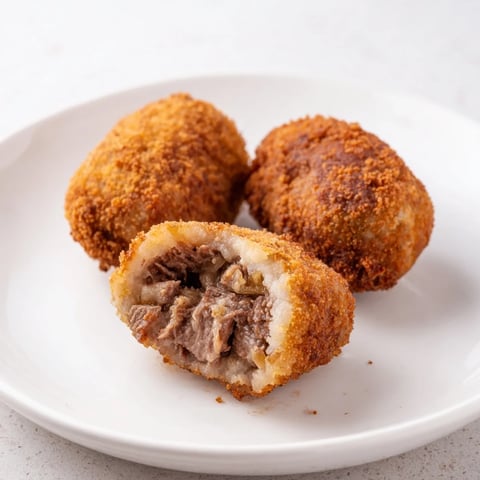 Golden-brown Dutch croquettes, crispy breadcrumb exterior, revealing a warm, creamy beef ragout inside.