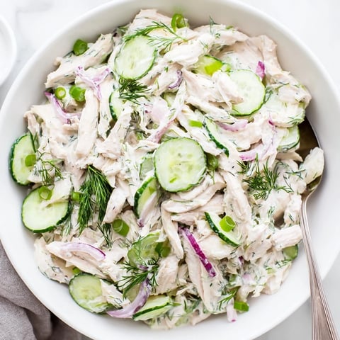 Chilled Creamy Cucumber Chicken Salad in a white bowl, garnished with fresh dill and green onions.