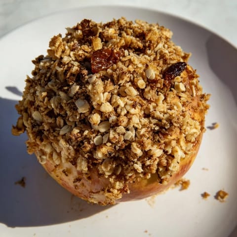 A close-up of baked apples with oat-nut crumble, ready to serve for a comforting dessert.