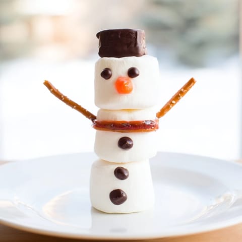 A colorful Marshmallow Snowman Stick Arrangement showcases festive snowmen decorated with tasty chocolate hats.