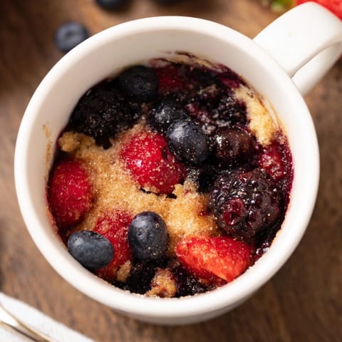 A delicious individual Mixed Berry Cobbler Mug Cake, with a perfectly cooked berry filling, ideal for a quick dessert.