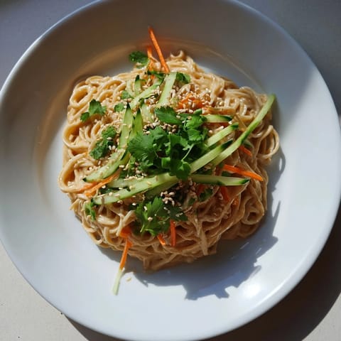 This recipe photo shows a serving of cold sesame noodles, boasting colorful julienned vegetables and fresh cilantro.