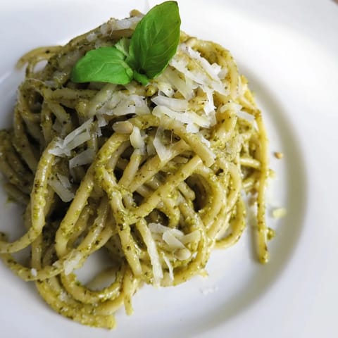 A vibrant green pesto sauce coats spiral fusilli pasta, with sunflower seeds and garlic adding a savory, nutty depth to this Italian-inspired main dish.  
