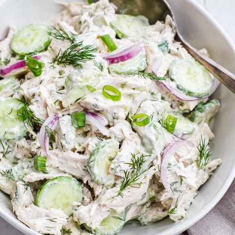 A fork lifts a bite of Creamy Cucumber Chicken Salad with crisp cucumber slices and tender chicken.