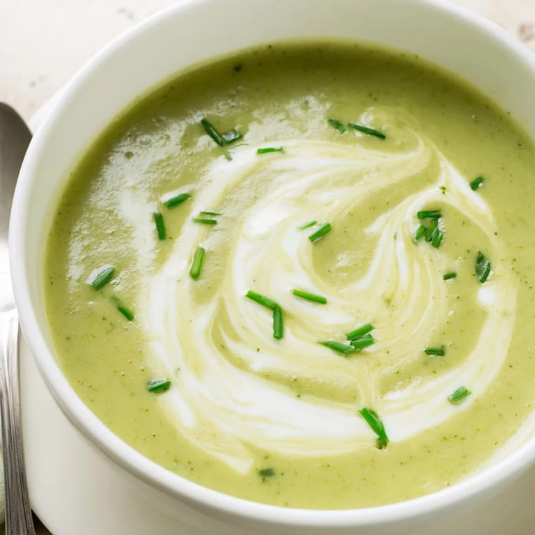 Close-up of creamy broccoli soup in a white bowl, garnished with croutons, ideal for a cozy vegetarian dinner.